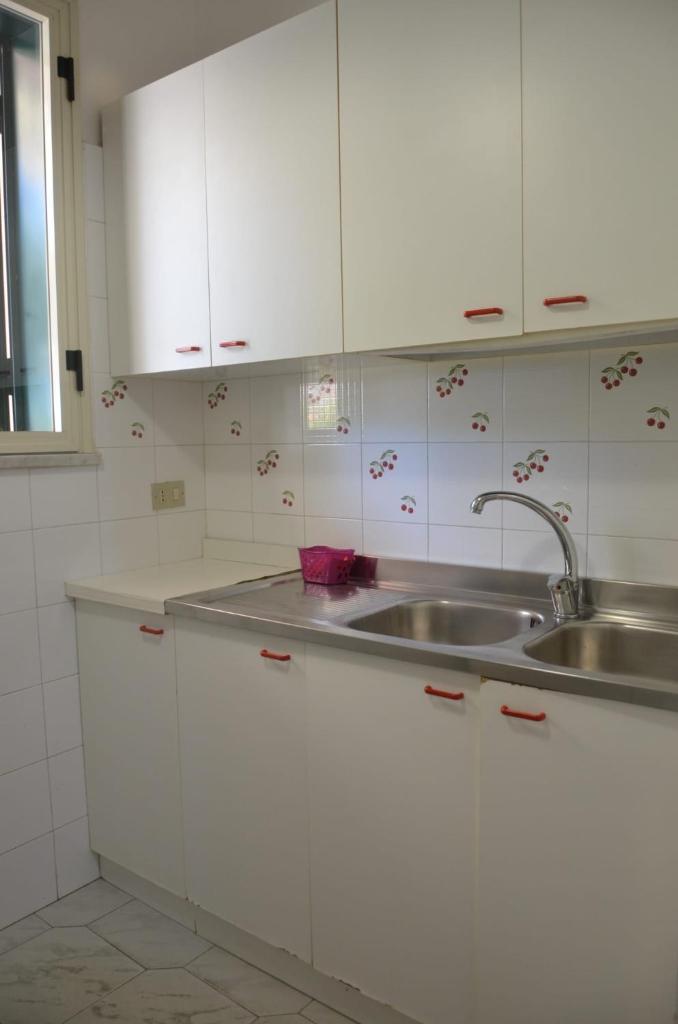 une cuisine avec des armoires blanches et un évier dans l'établissement Villa Teti - Sicilia, à Campofelice di Roccella