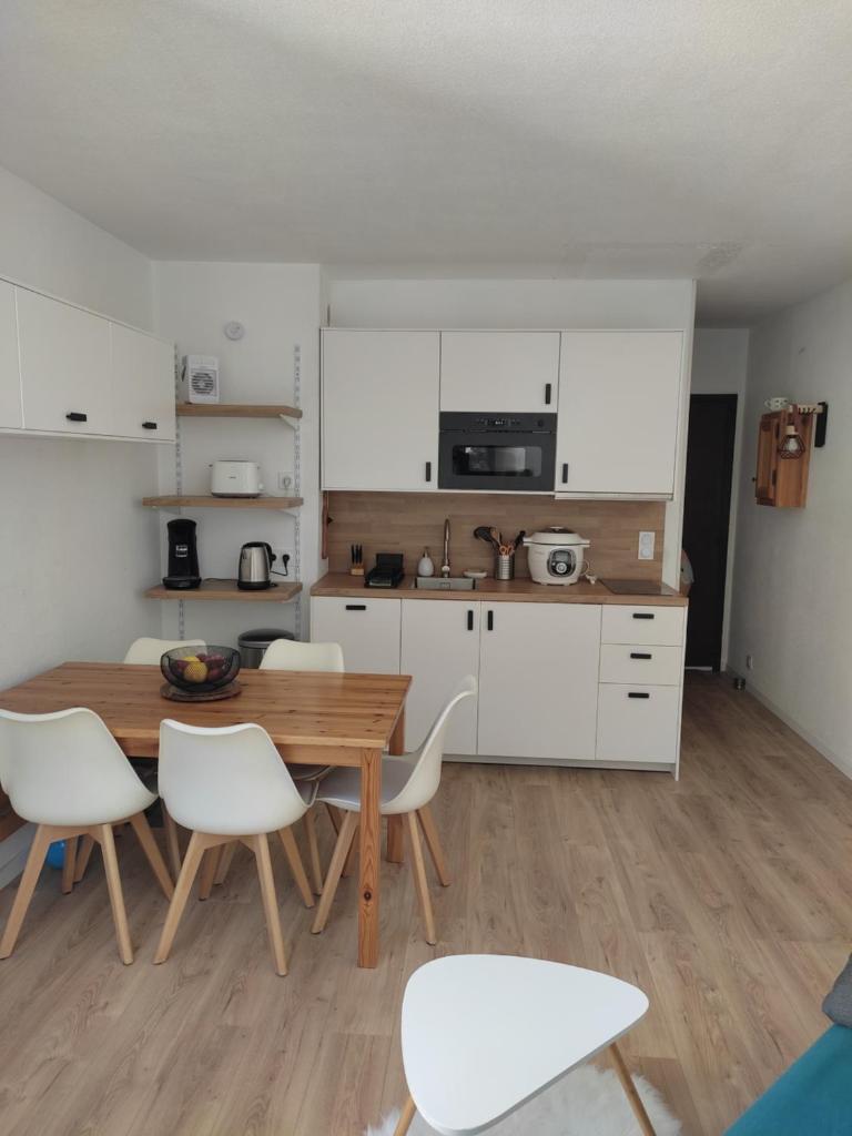une cuisine avec une table en bois et des armoires blanches dans l'établissement Très beau T2 rénové pour 7 personnes maximum à Barèges, à Barèges