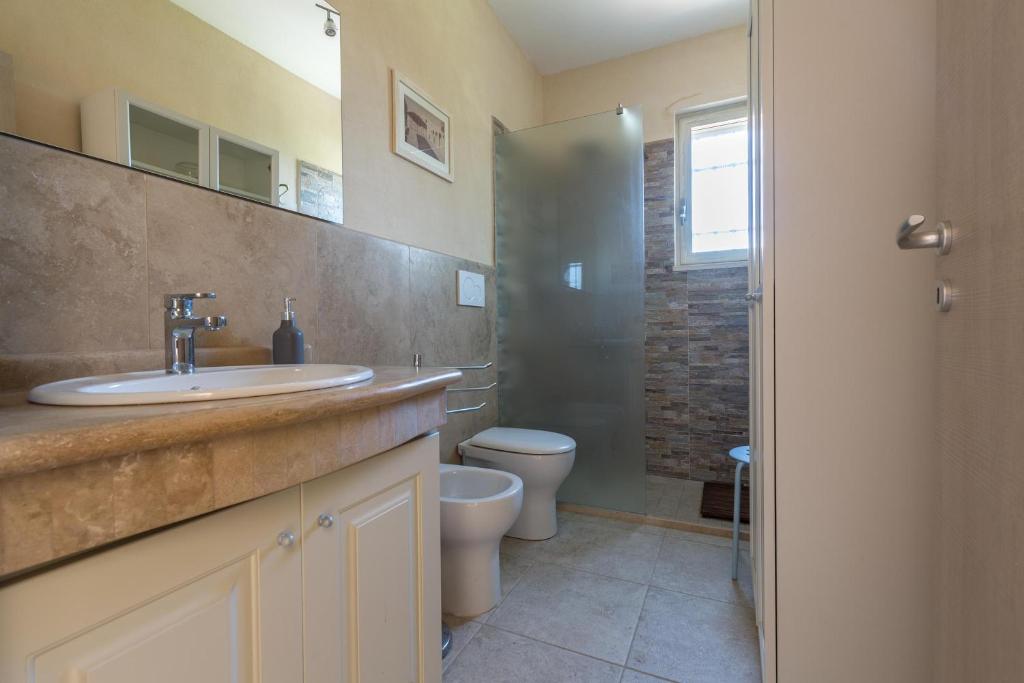 une salle de bain avec un lavabo, des toilettes et une douche dans l'établissement Villa Le Majole by Perle di Puglia, à Mandurie