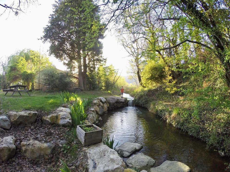 un ruisseau d'eau avec des rochers dans un parc dans l'établissement Roulotte Tzigane au bord du ruisseau - Drôme Provençale (2p), à Marsanne