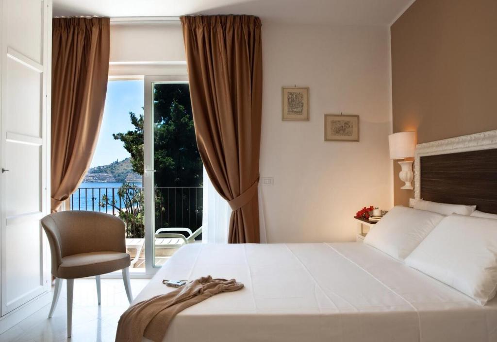 une chambre avec un lit, une chaise et une fenêtre dans l'établissement Taormina Villa Oasis Residence, à Taormine
