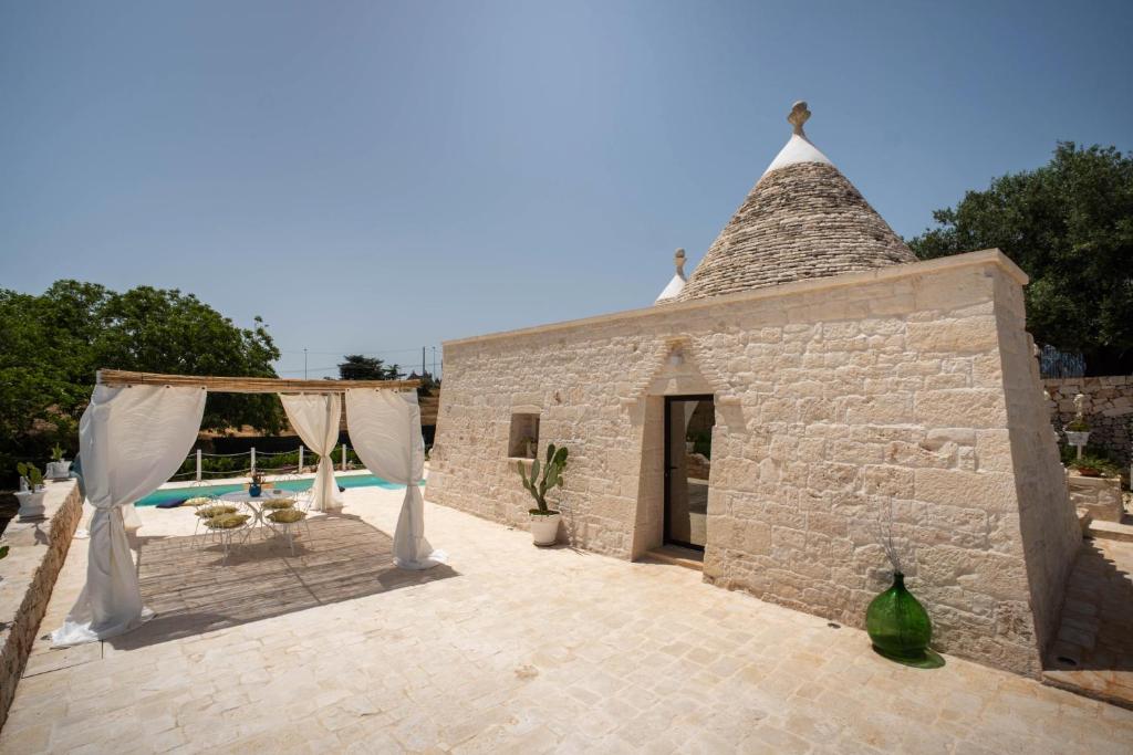 un bâtiment en pierre avec un chapiteau et une piscine dans l'établissement WePuglia - Trullo Meraviglioso, à Martina Franca