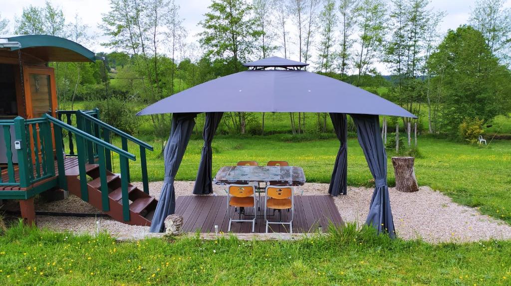 une table et des chaises dans un gazebo dans une aire de jeux dans l'établissement Roulotte de la Petite Beauronne, à Les Lèches
