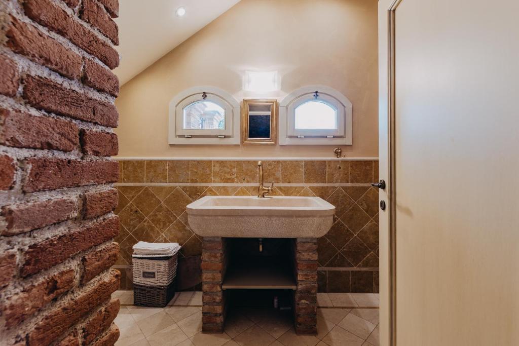 La salle de bains est pourvue d'un lavabo et d'un mur en briques. dans l'établissement Villa Mocasina - 25 m Pool, à Calvagese della Riviera