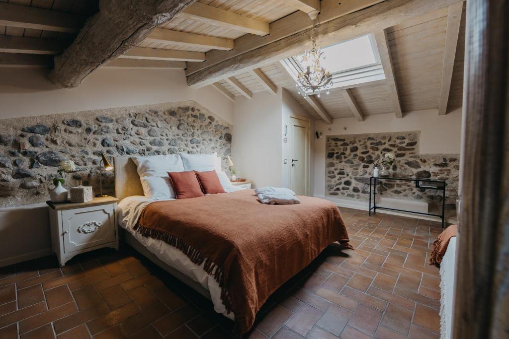 une chambre avec un grand lit et un mur en pierre dans l'établissement Villa Mocasina - 25 m Pool, à Calvagese della Riviera