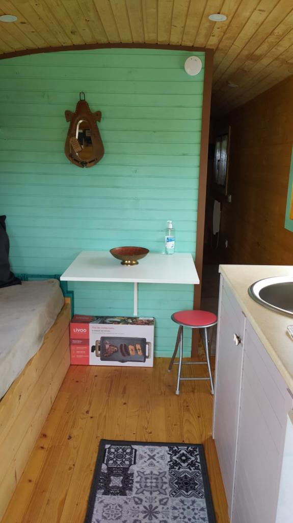 Cette chambre comprend un lit, une table et un lavabo. dans l'établissement Roulotte de la Petite Beauronne, à Les Lèches