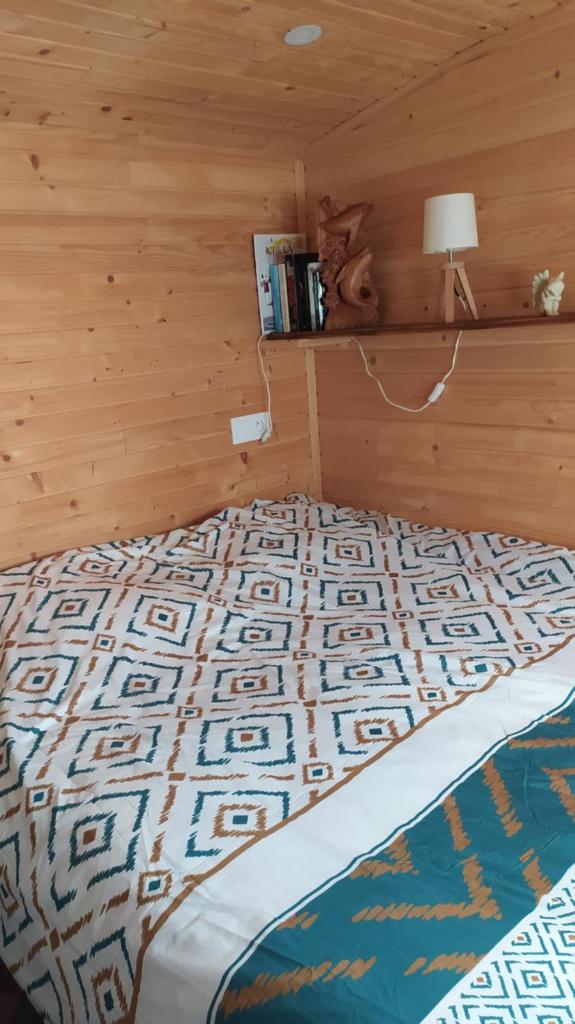 - une chambre avec un lit et un mur en bois dans l'établissement Roulotte de la Petite Beauronne, à Les Lèches