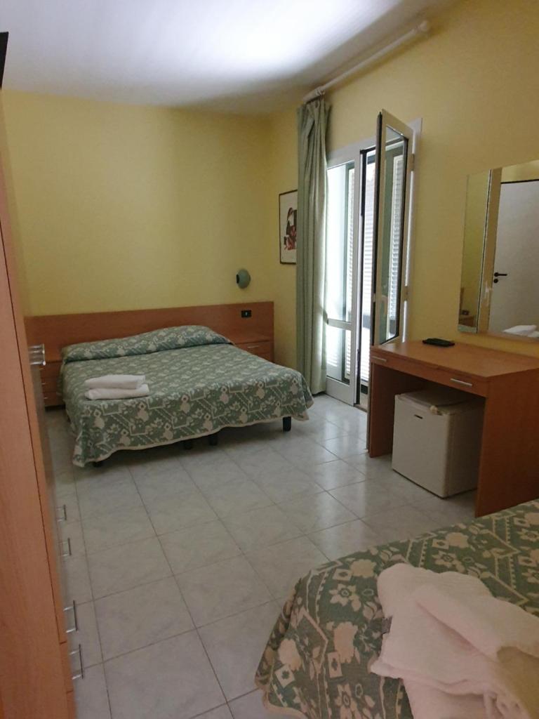 une chambre d'hôtel avec deux lits et un miroir dans l'établissement Hotel Il Timone, à Specchiolla