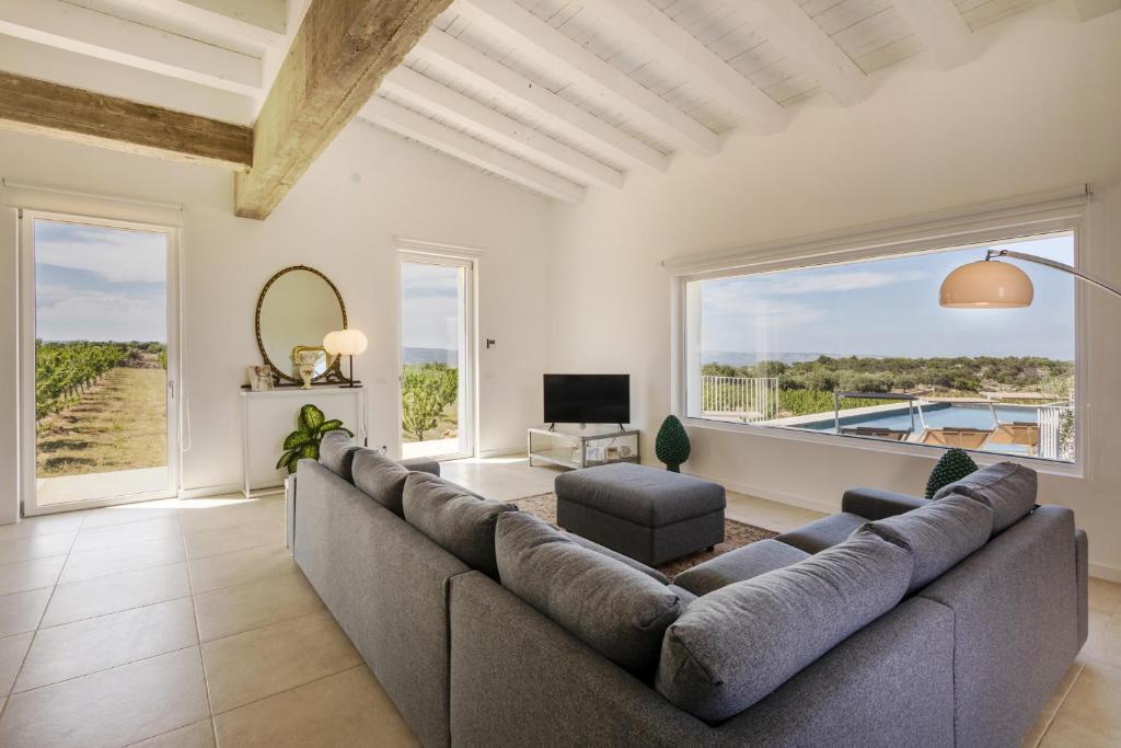 - un salon avec un grand canapé et une grande fenêtre dans l'établissement Villa Mandorlo - IsulaTravel, à Noto