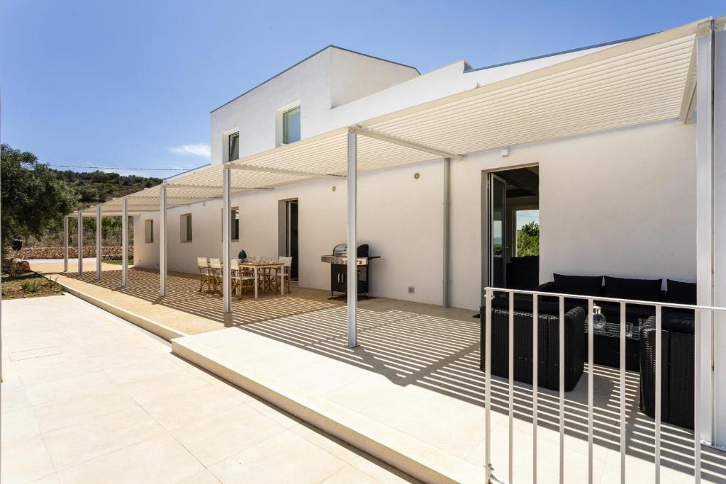 une maison blanche avec une clôture sur un patio dans l'établissement Villa Mandorlo - IsulaTravel, à Noto