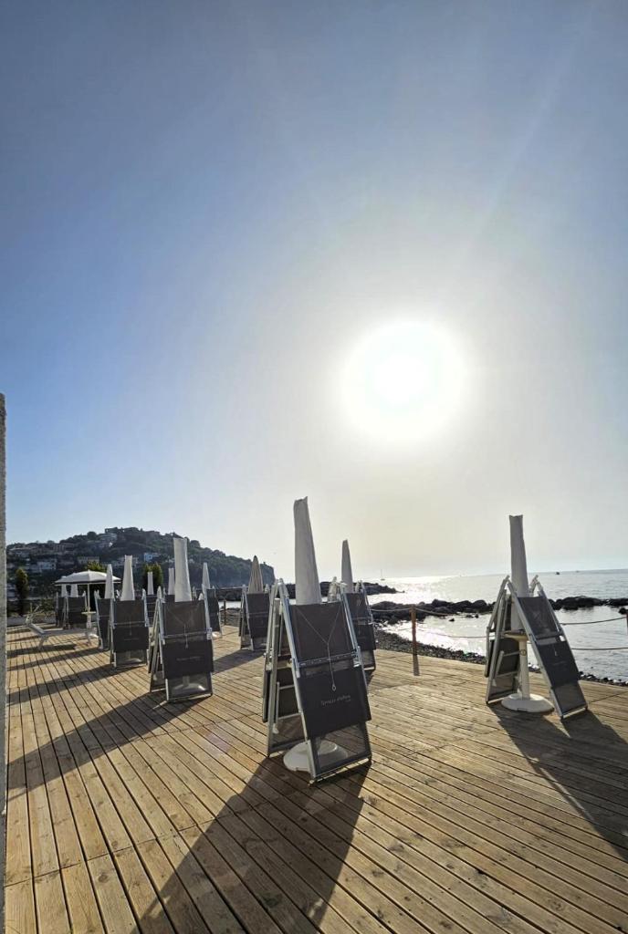 une rangée de chaises assises sur une jetée en bois à côté de l'océan dans l'établissement Hotel Mare, à Agropoli