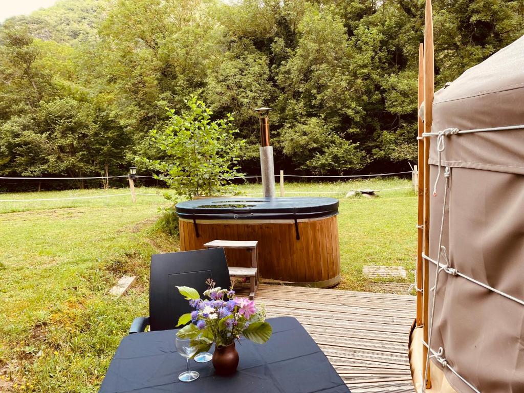 une table et des chaises sur une terrasse avec un bain à remous dans l'établissement Yourte et son bain nordique, à Fréchet-Aure 19 autres photos