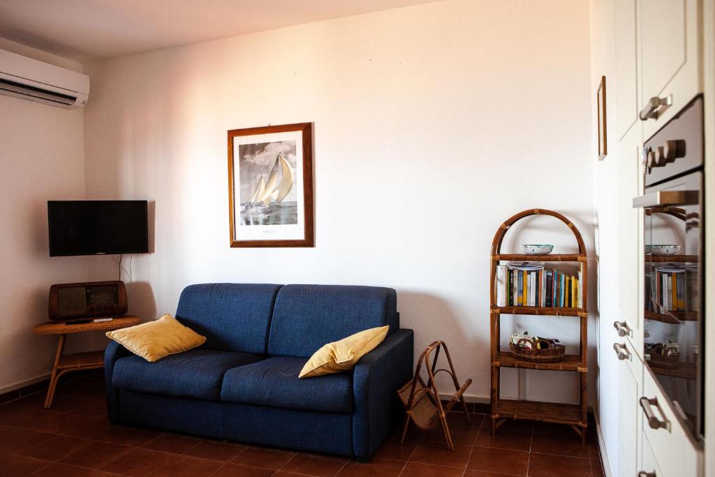 un canapé bleu dans un salon avec une télévision dans l'établissement Villa Arianna (Parghelia, Calabria), à Parghelia