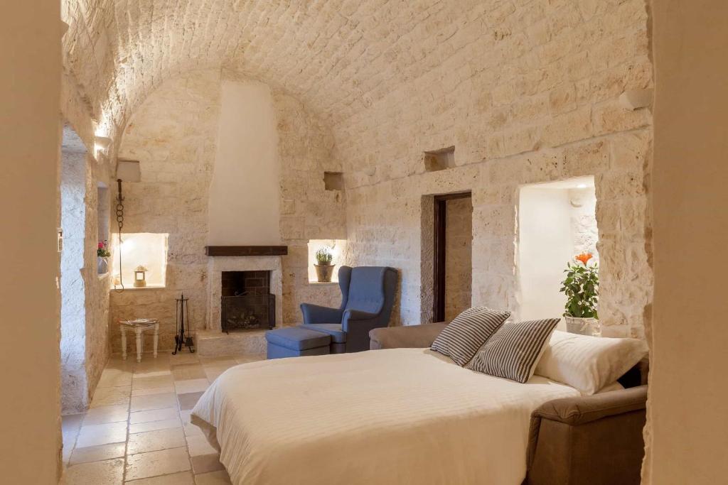une chambre avec un grand lit et un mur en pierre dans l'établissement Trullo Badessa, à Martina Franca