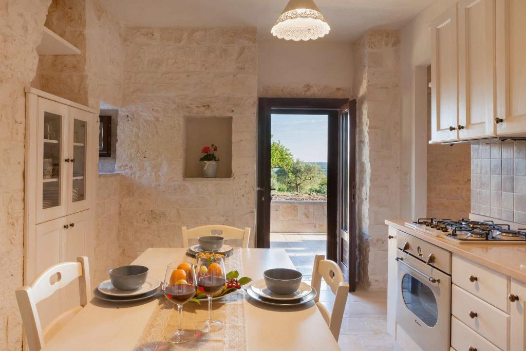 une cuisine avec une table et des chaises et une cuisine avec une fenêtre dans l'établissement Trullo Badessa, à Martina Franca