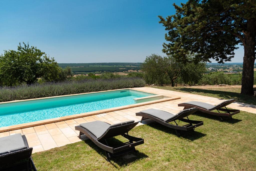 une piscine avec trois chaises longues à côté dans l'établissement Trullo Badessa, à Martina Franca