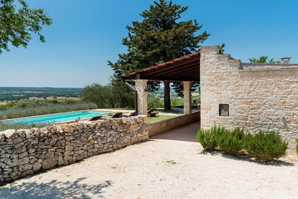 une maison en pierre avec une piscine et un mur en pierre dans l'établissement Trullo Badessa, à Martina Franca