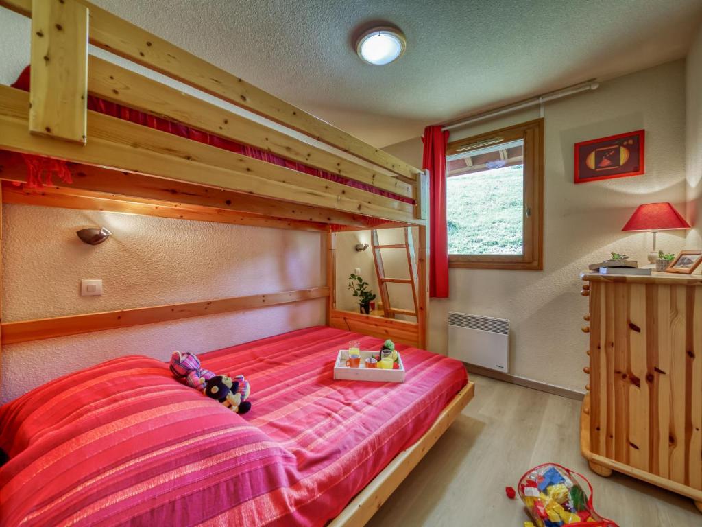 une chambre avec un lit superposé avec un couvre-lit rouge dans l'établissement Apartment Les Alpages du Corbier-1 by Interhome, au Corbier