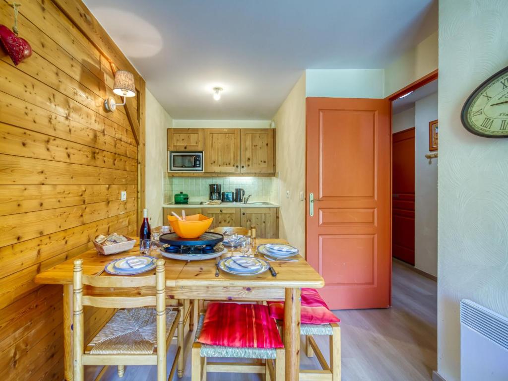 une cuisine avec une table et des chaises ainsi qu'une porte rouge dans l'établissement Apartment Les Alpages du Corbier-1 by Interhome, au Corbier