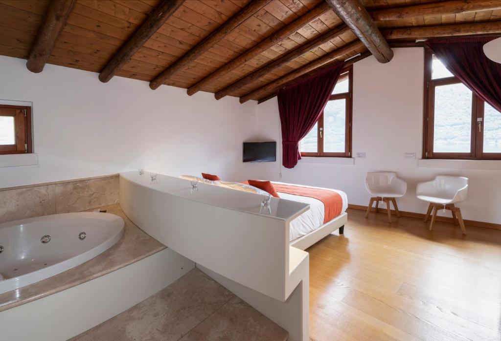 - une chambre avec une grande baignoire et un lit dans l'établissement Parco San Marco Lifestyle Beach Resort, à Porlezza