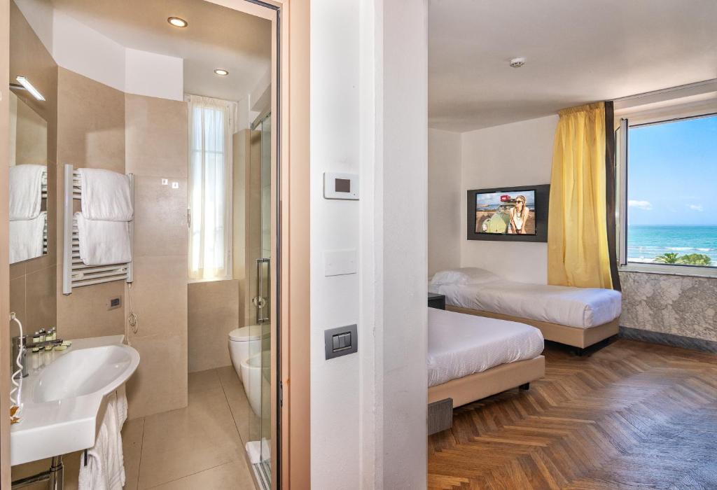 Cette chambre d'hôtel dispose d'une salle de bains avec un lit et une fenêtre. dans l'établissement Hotel Tirreno, à Marina di Massa