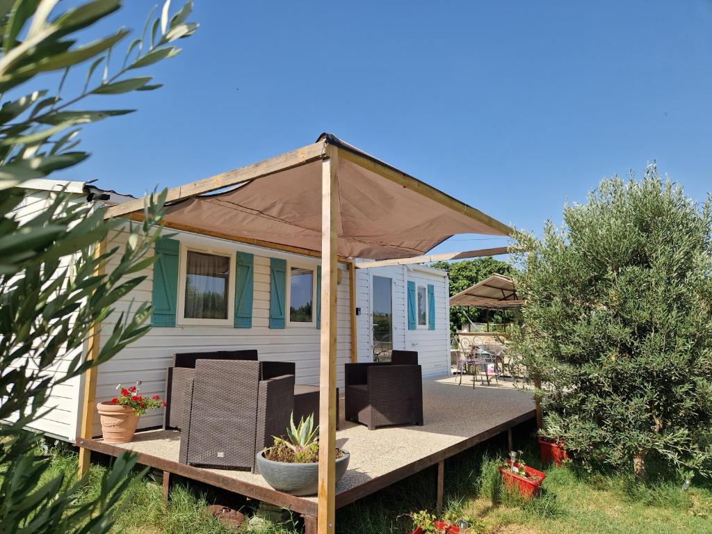 une petite maison blanche avec un parasol sur une terrasse dans l'établissement Mazet d El gato, à Arles