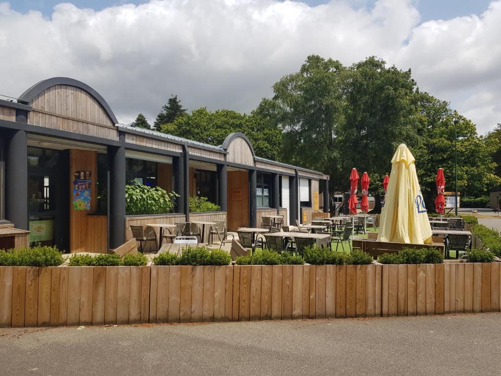 un restaurant avec une table et un parasol jaune dans l'établissement Mobilhome 6 places dans camping 4* Finistère Sud, à Saint-Yvy