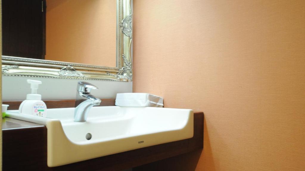 une salle de bain avec un lavabo blanc et un miroir dans l'établissement Yourou Onsen Honkan, à Onomichi