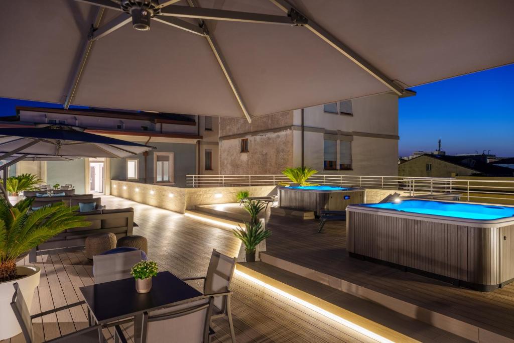 une terrasse sur le toit avec un bain à remous et des tables dans l'établissement Vi Suites, à Viareggio