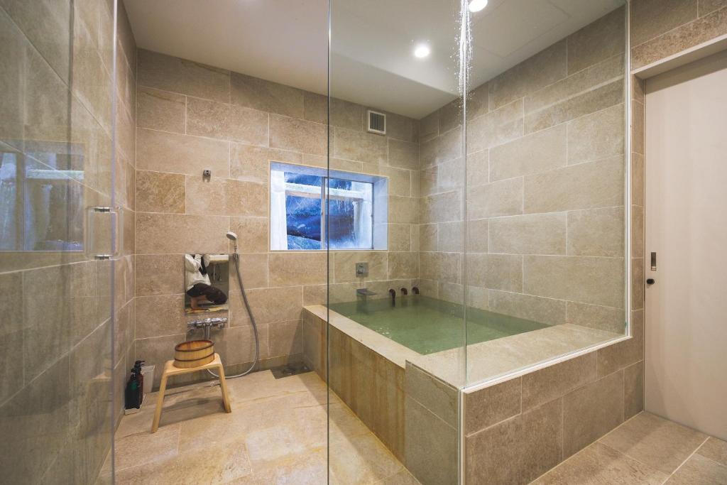 La salle de bains est pourvue d'une douche en verre et d'un tabouret. dans l'établissement Ryokan Masuya, à Ōda