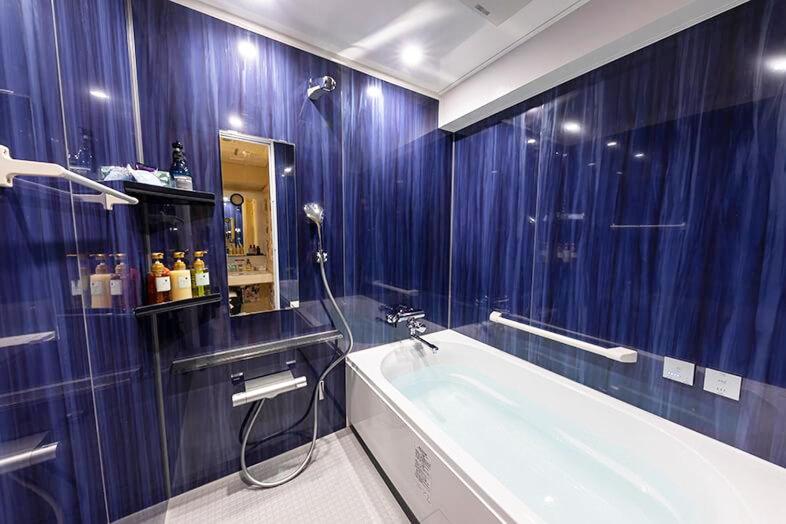 La salle de bains bleue est pourvue d'une baignoire et d'une douche. dans l'établissement Hotel Next II, à Sendai
