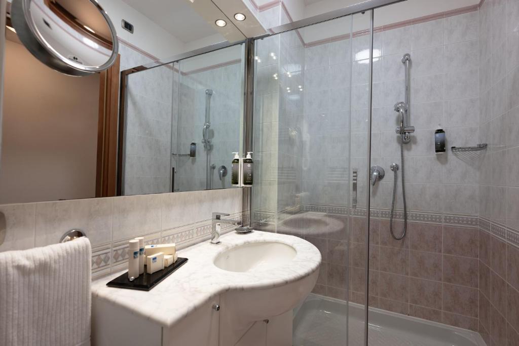 une salle de bain avec un lavabo et une douche en verre dans l'établissement Savoy Beach Hotel & Thermal Spa, à Bibione