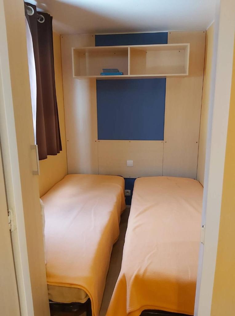 une petite chambre avec deux lits et une télévision dans l'établissement vacances familiales dans camping avec piscine, à Fréjus