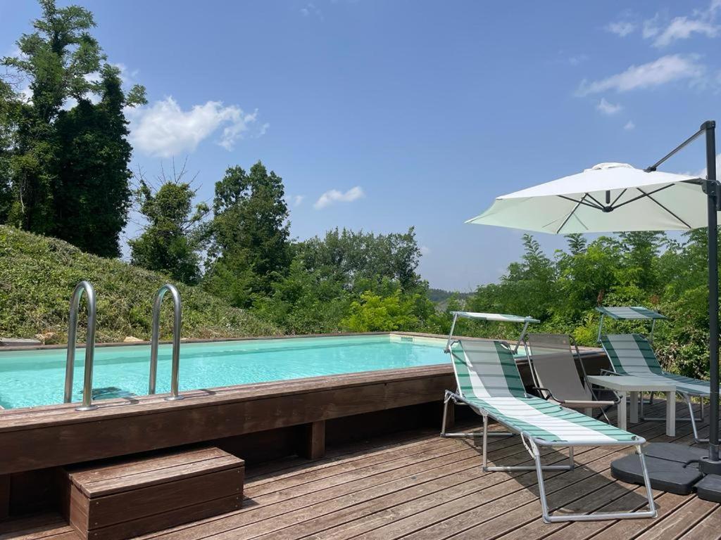- une paire de chaises et un parasol à côté de la piscine dans l'établissement Casale IL SAMBUCO sui colli bolognesi, à San Lazzaro di Savena