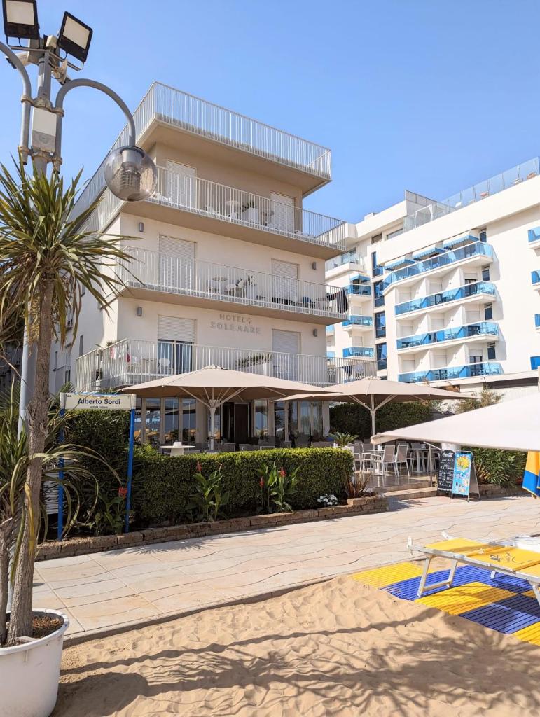 un grand bâtiment avec un palmier devant dans l'établissement Hotel Solemare - Frontemare - 3 Stelle Superior, à Lido di Jesolo