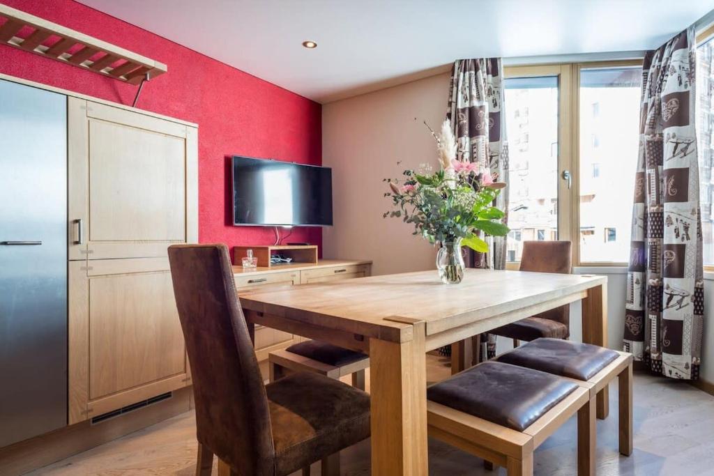 une salle à manger avec une table en bois et une télévision dans l'établissement IMMODREAMS - Le Refuge, à Morzine 9 autres photos