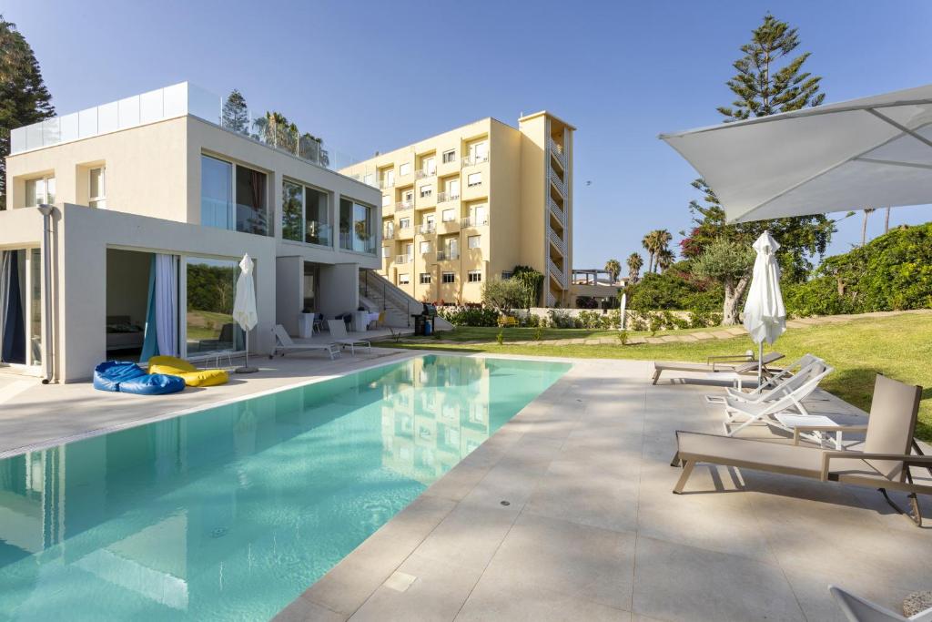une piscine avec des chaises et un parasol et un bâtiment dans l'établissement Dimora di Eos - IsulaTravel, à Noto