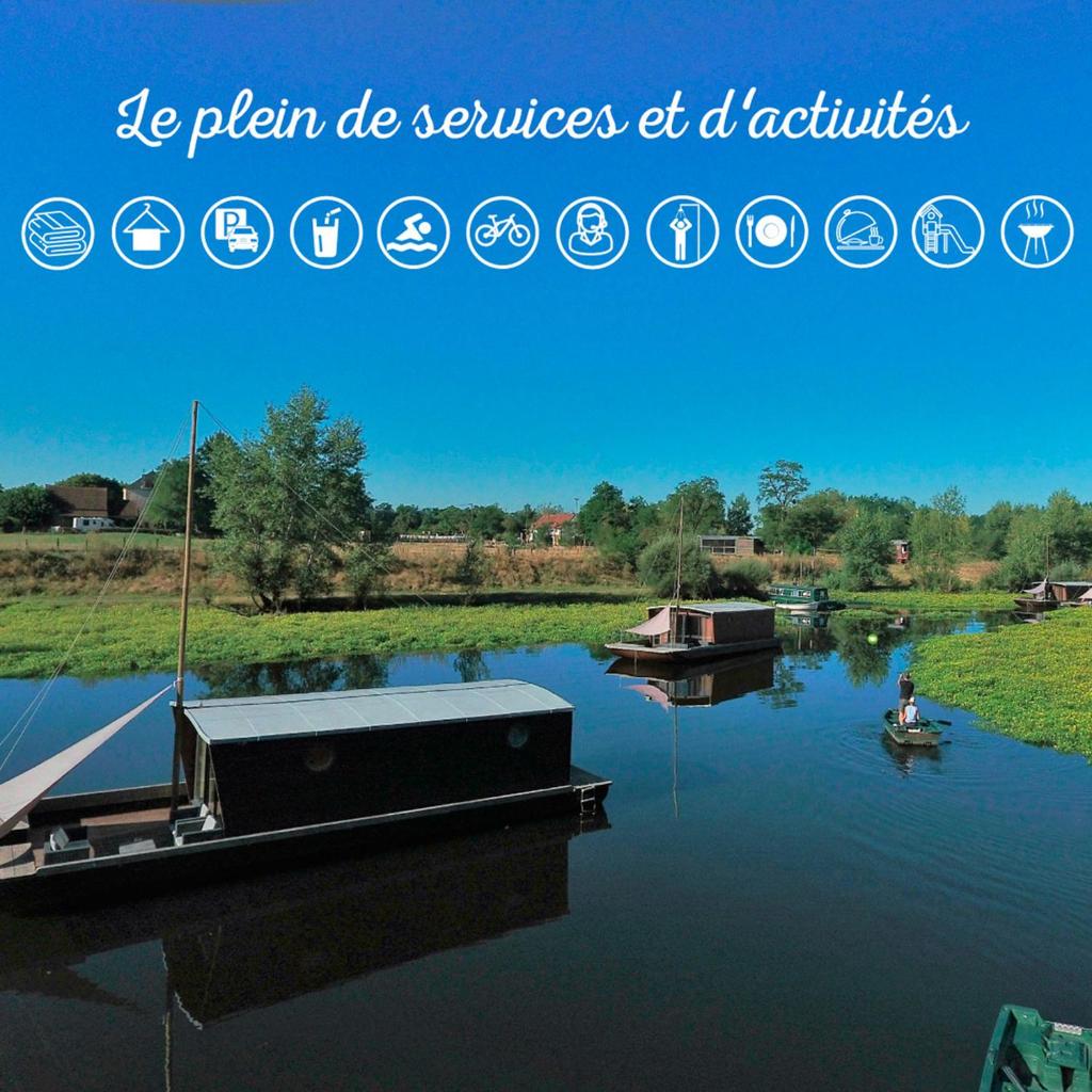 une photo d'une rivière avec un bateau sur l'eau dans l'établissement Village Toue du Domaine des Demoiselles, à Chassenard