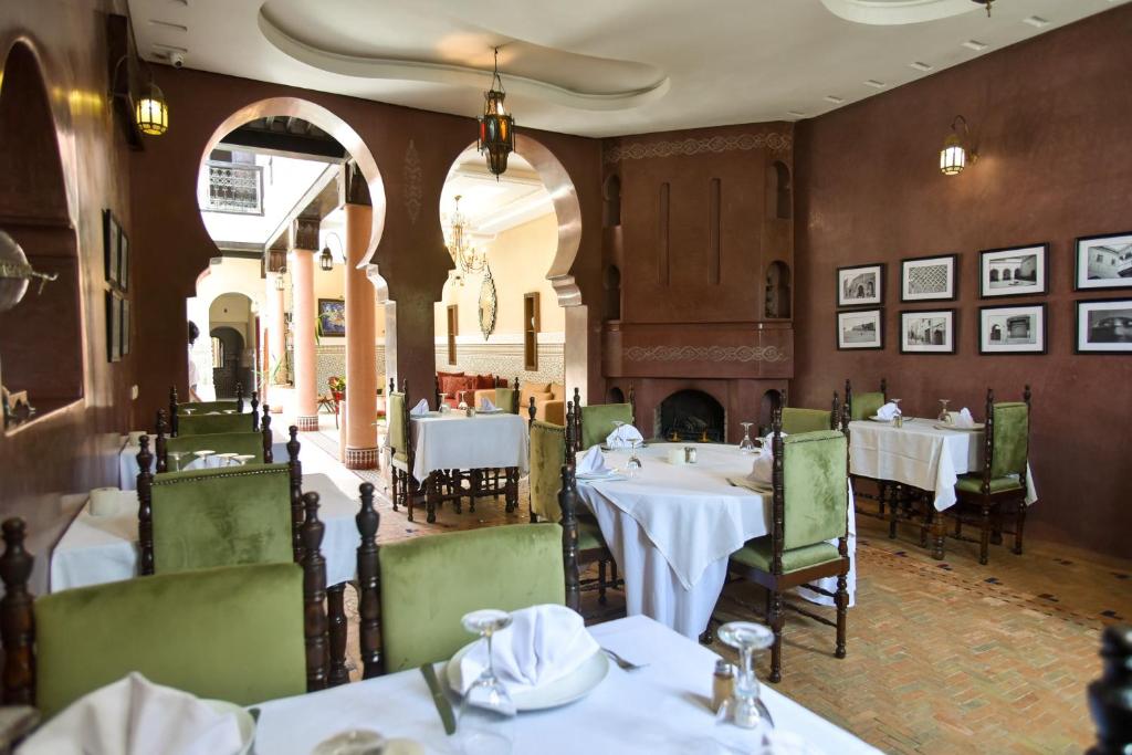 un restaurant avec des tables blanches et des chaises vertes dans l'établissement Riad Yacout, à Meknès
