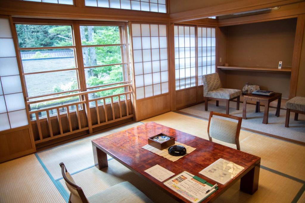 une pièce avec une table, des chaises et des fenêtres dans l'établissement Houshi Onsen Chojukan, à Minakami