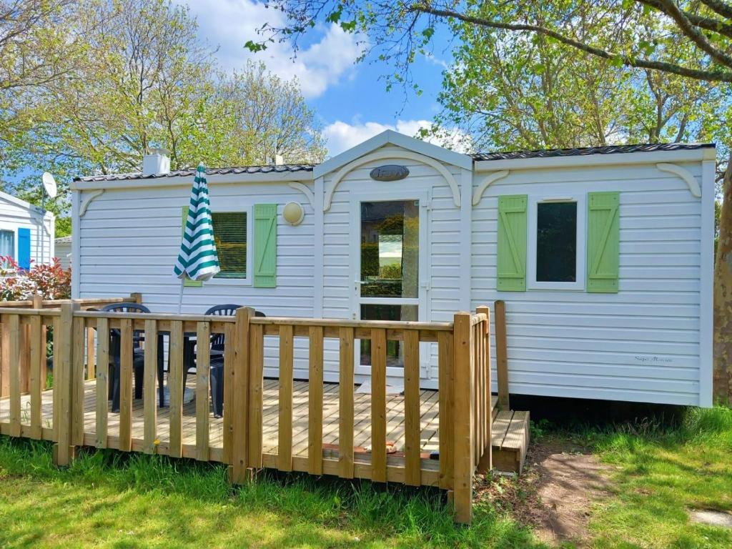 une petite maison blanche avec une clôture en bois dans l'établissement Mobil home 5-6 personnes, à Carnac