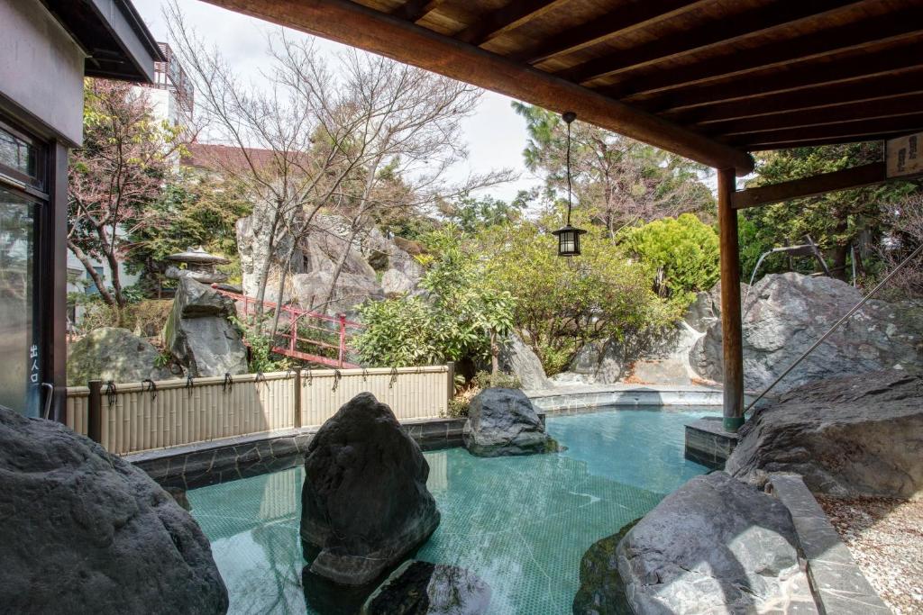 - une piscine avec des rochers dans l'arrière-cour dans l'établissement Hotel Heian, à Fuefuki