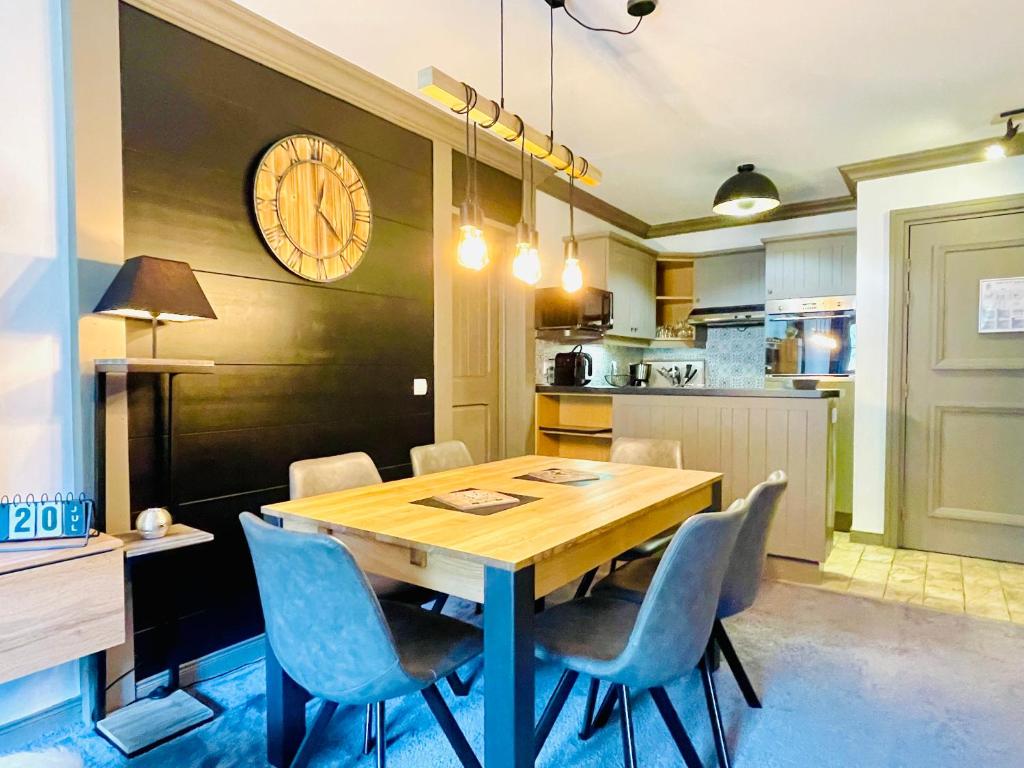 une table à manger avec des chaises et une horloge murale dans l'établissement ARC 1950 Appt 6/8 pers LUXE MANOIR SAVOIE - SKI IN SKI OUT, à Arc 1950
