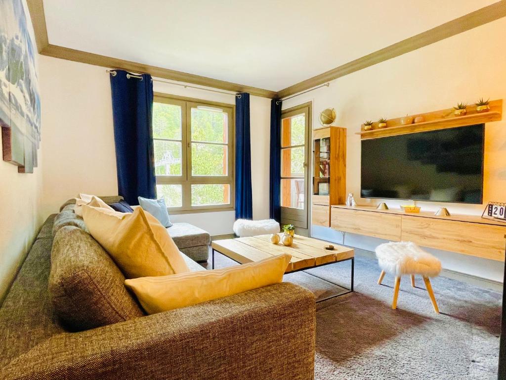 - un salon avec un canapé et une grande télévision dans l'établissement ARC 1950 Appt 6/8 pers LUXE MANOIR SAVOIE - SKI IN SKI OUT, à Arc 1950