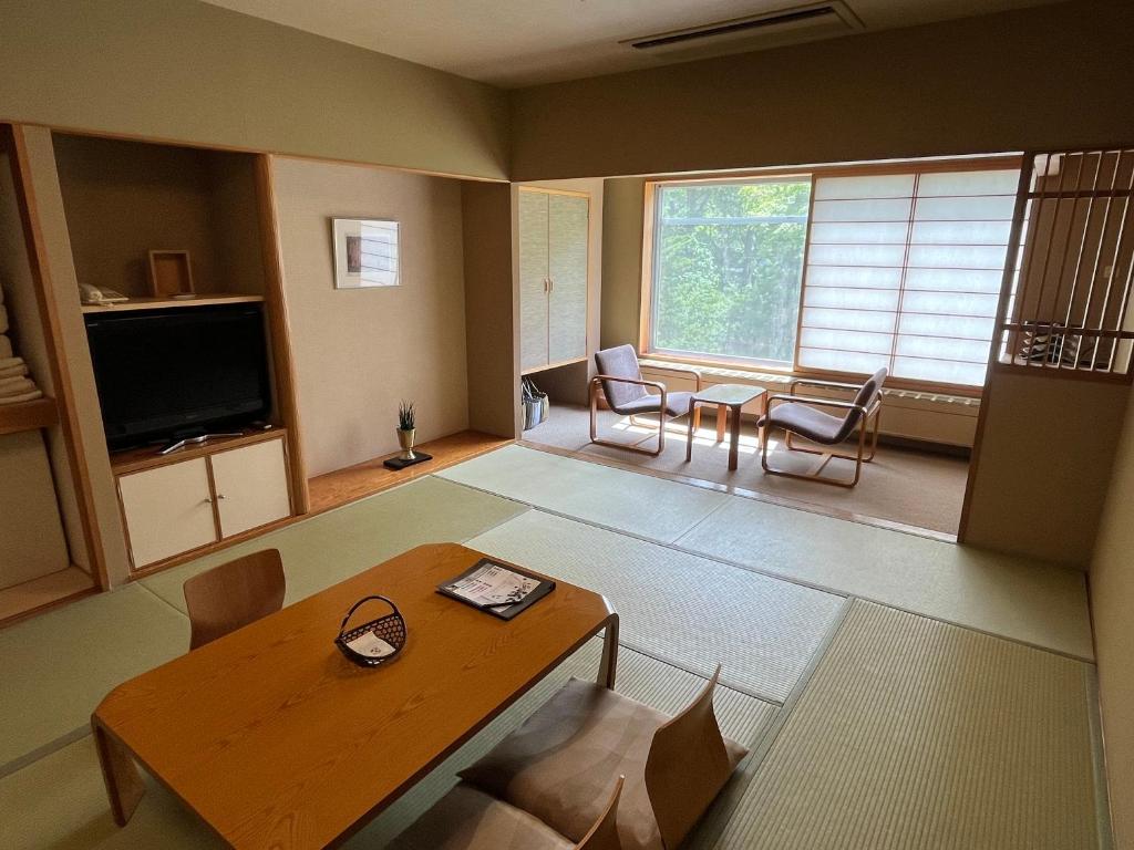 un salon avec une table, des chaises et une télévision dans l'établissement Spa and Esthetique Suichokan-Female&Adult Only, à Jozankei