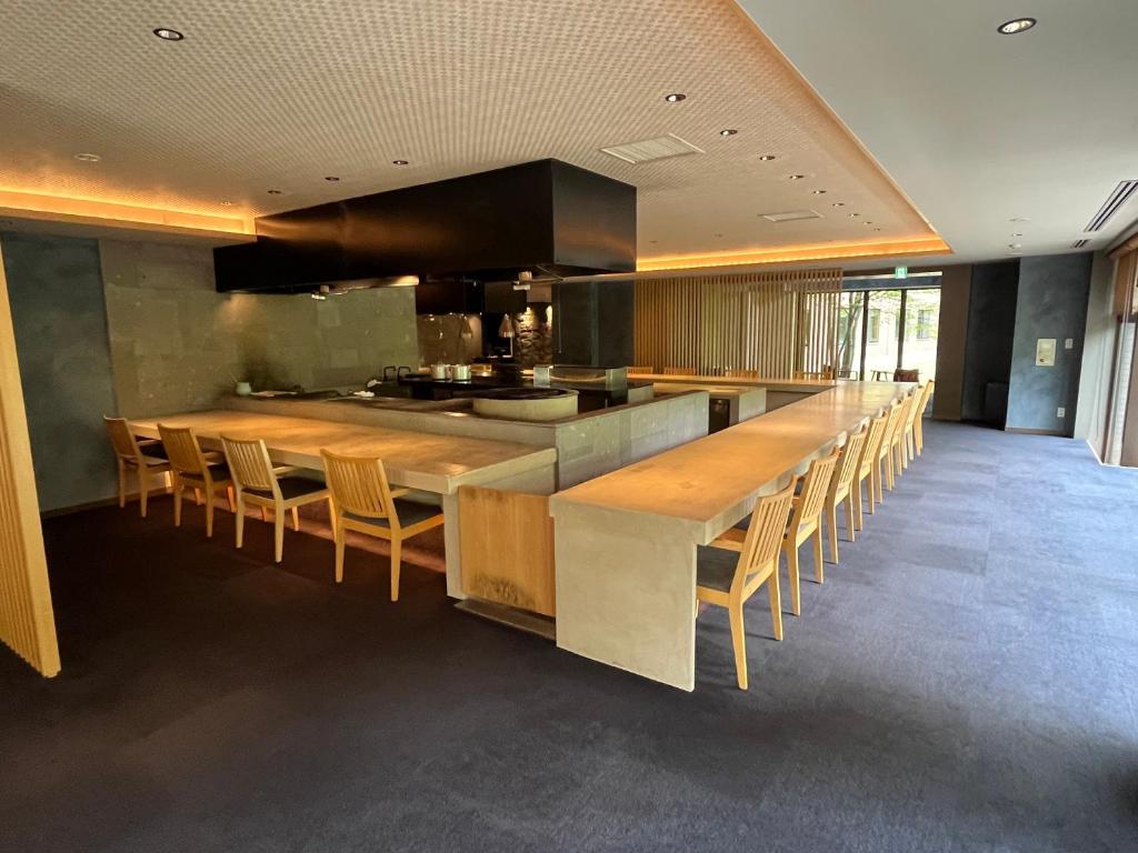 une cuisine avec un long bar avec des tables et des chaises en bois dans l'établissement Kuriya Suizan, à Jozankei