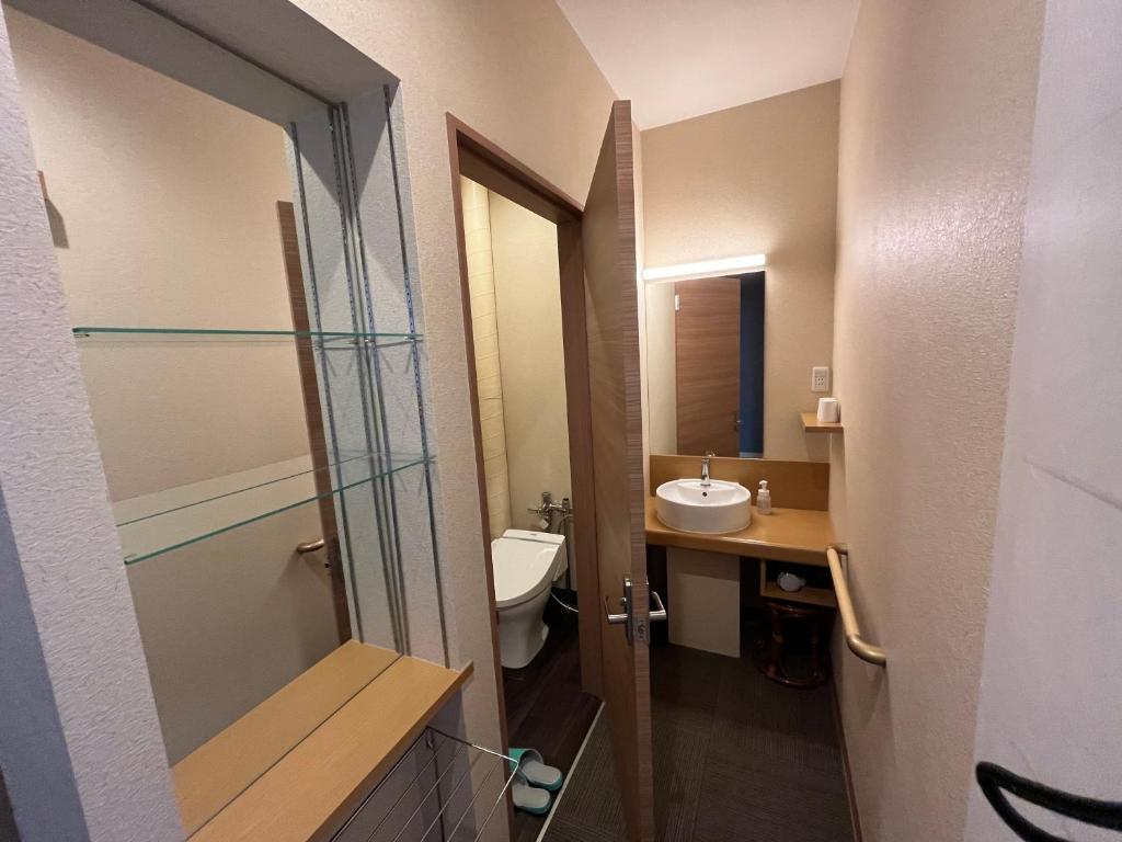 une salle de bain avec un lavabo, des toilettes et un miroir dans l'établissement Sapporo's Secret Onsen Sanctuary Marukoma Onsen Ryokan, à Chitose