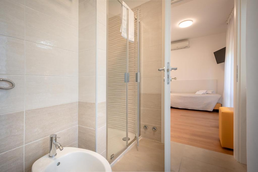 une salle de bain avec une douche avec un lavabo et des toilettes dans l'établissement Hotel Royal Garnì, à Caorle