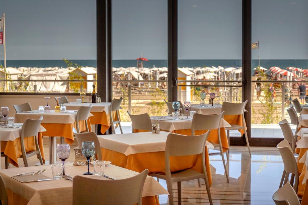 un restaurant avec des tables et des chaises et la plage dans l'établissement Hotel Parigi, à Caorle