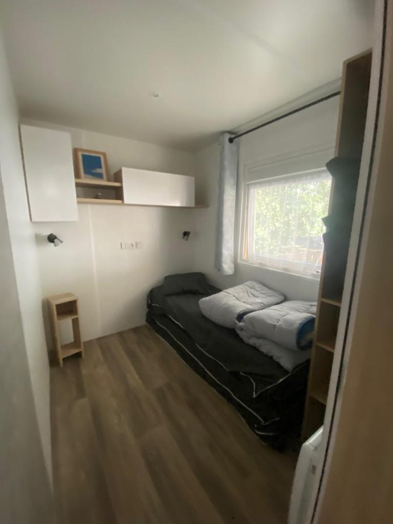 une petite chambre avec deux lits et une fenêtre dans l'établissement Mobil-home Les Dunes de Contis, à Saint-Julien-en-Born